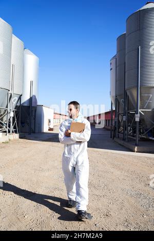 Worker in protective suit at factory on sunny day Stock Photo