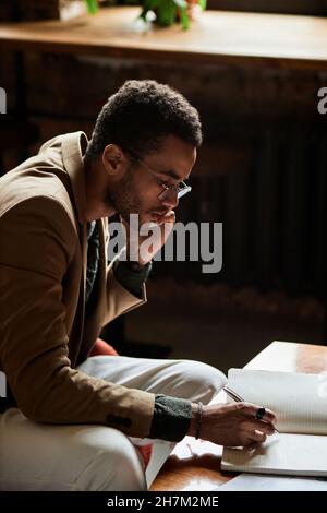 Young man talking on smart phone and writing notes in notebook Stock Photo