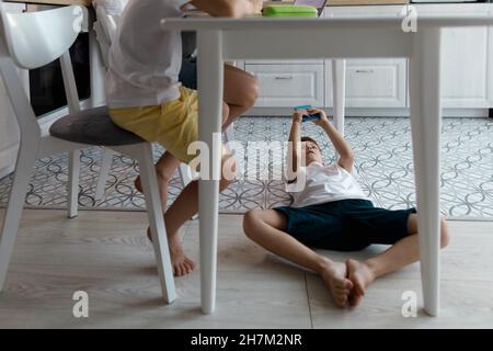 Boy using mobile phone under table lying on floor Stock Photo