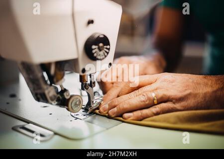 Fashion designer sewing clothes on machine in workshop Stock Photo