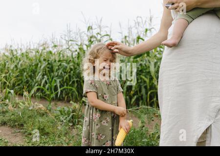 Upset girl crying by mother in corn field Stock Photo