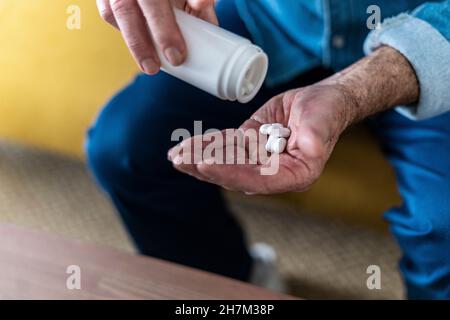 Senior man holding glass of water taking medicine at home Stock Photo