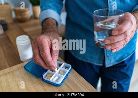 Senior man with glass of water and medicine at home Stock Photo