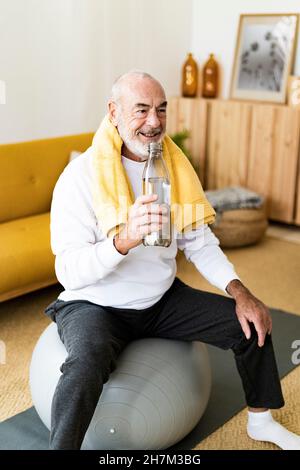 Active senior man exercising on fitness ball at home Stock Photo