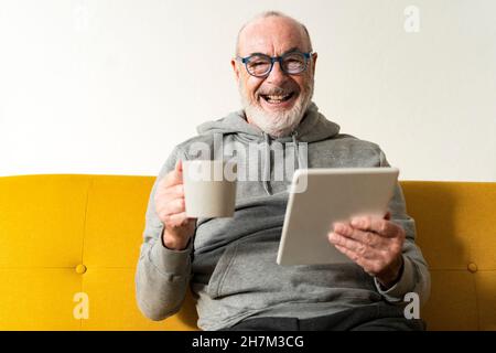 Bearded senior man doing online shopping through tablet PC at home Stock Photo