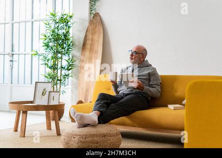 Man with coffee cup using tablet PC in living room Stock Photo