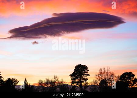 A wispy, feather-like cloud adds whimsical interest to this colorful Colorado sunset. Stock Photo