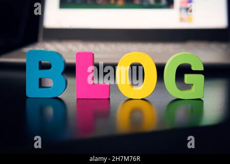 The word blog on a black table against a gray laptop. The concept of video blogging development in the world. macro Stock Photo