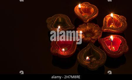 Hindu religion and Indian celebration of Diwali festival concept with group of burning clay diyas, which are festive oil lamps with illumination and r Stock Photo