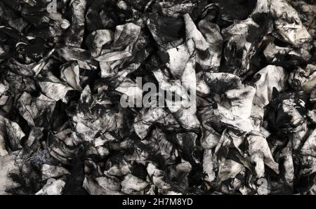 A mass of dirty used cloth wipes covered in black printers ink. Could also be oil dipstick wipes from mechanic. Unique abstract black and white backgr Stock Photo
