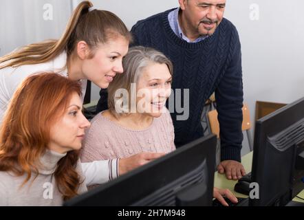 Young and mature business people grouped around computer monitor Stock Photo