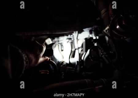 Shining a light into the open hood of vehicle to check the engine Stock Photo