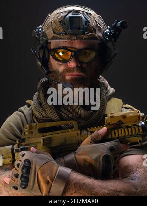 Portrait of an American soldier against the dark concrete background. He holds his weapon and looks straight into the camera. Veterans Memorial Day co Stock Photo