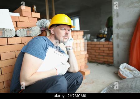 Upset worker sit surrounded with construction site mess with paper Stock Photo