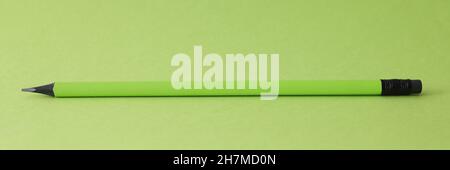 Sharp simple pencil lying on green background closeup Stock Photo