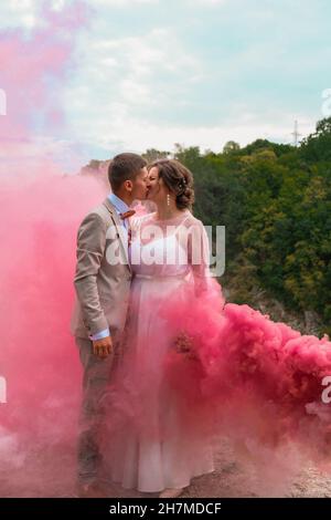Wedding couple kissing with color smoke in the summer park Stock Photo ...