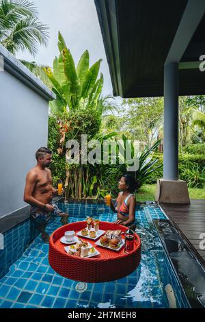 floating breakfast in plunge pool, afternoon tea or floating breakfast in swim pool. man and woman having breakfast in pool Stock Photo