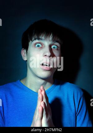 Toned Photo of Frightened Young Man in the Dark Room Stock Photo