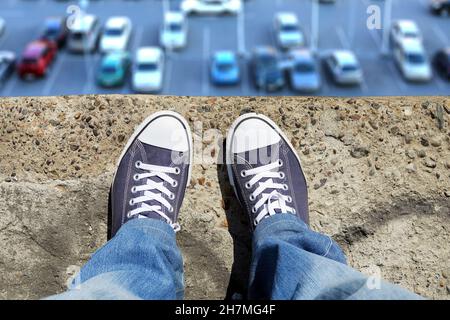 Person in the Jeans and Sneakers on the Edge Stock Photo