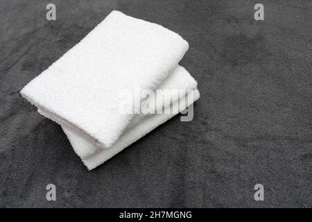 Three white towels on the gray plaid at the hotel's room Stock Photo
