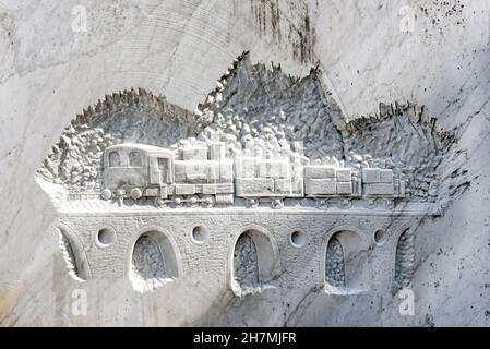 Train with cargo driving on arched railroad bridge carved on white marble wall Stock Photo