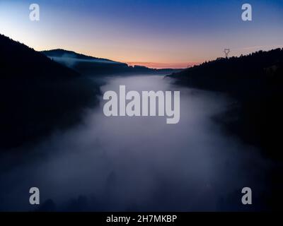 Peaceful aerial drone view of a valley in the fog in the french mountains of Vosges at sunset Stock Photo