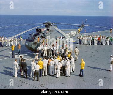 (18 Dec. 1965) --- The crew of the Gemini-7 spaceflight, astronauts Frank Borman, command pilot, and James A. Lovell Jr., pilot, arrive aboard the aircraft carrier USS Wasp. The astronauts were picked up from the ocean, following successful splashdown, by recovery helicopter and flown to the carrier to begin postflight medical and technical debriefings Stock Photo