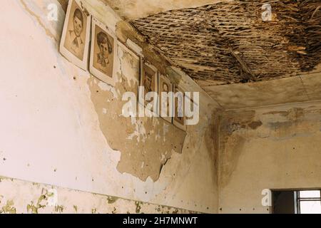 Six Black And White Paper Portraits Of Young Pioneers, Heroes Of WW2 War On Cracked Peeling Wall In Classroom Of Abandoned School After Chernobyl Stock Photo