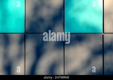 Grey and turquoise alternating squares. Abstract shadows on the exterior wall of the building. The building is clad in multicolored metal sheets. Arch Stock Photo