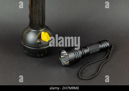 Small Modern tactical and large obsolete flashlights on gray background. Selective Focus. Stock Photo