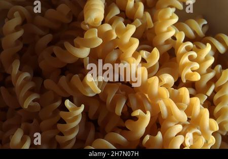 Raw Italian Pasta on dark light. Fusilli pasta. Stock Photo