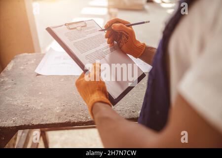 Male worker hands in gloves writing on clipboard Stock Photo