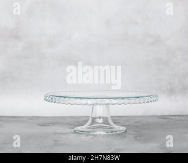 Empty glass pastry cake stand on light plain background. Horizontal frame copy space Stock Photo