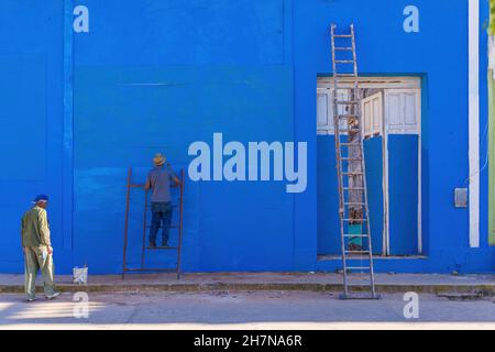 TRINIDAD, CUBA - JANUARY 7, 2021: Cuban worker painting outside of house in blue color on Janaury 7th, 2021 in Trinidad. Houses in Cuba have to be Stock Photo