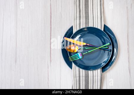 Dining set with blue plates and iridescent cutlery on white wooden table Stock Photo