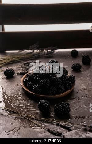 selective focus, blackberries on a wooden plate. on a dark background, copyspace. Low Key Stock Photo