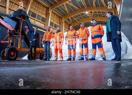 24 November 2021, Mecklenburg-Western Pomerania, Consrade: Reinhard Meyer (SPD, r), the Minister of Economics and Transport of Mecklenburg-Western Pomerania, stands with employees of the winter road clearance service at a photo opportunity in the hall for road salt on the premises of the road maintenance depot. He informed himself on site about the preparations for the winter. Around 24,000 tons of salt are stored in the 25 road maintenance depots in Mecklenburg-Western Pomerania. In the coming months, more than 500 employees will be working in the winter service to keep the roads clear. Photo Stock Photo