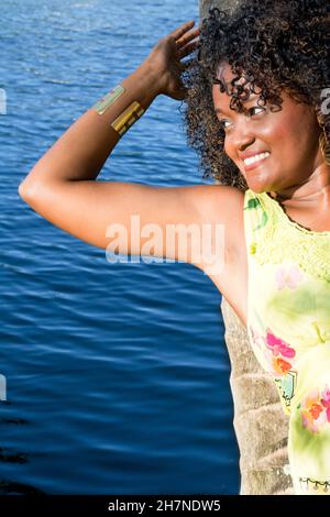 Black woman posing for photo. She wears yellow, smiles and looks at the camera. Salvador, Bahia, Brazil. Stock Photo
