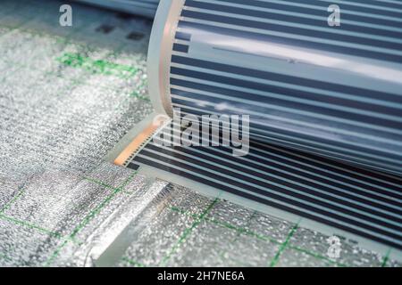 A roll of film underfloor heating lies on the insulation Stock Photo