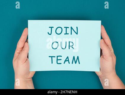 The words join our team are standing on a paper, yellow colored background, hands hold message, recruiting employee Stock Photo