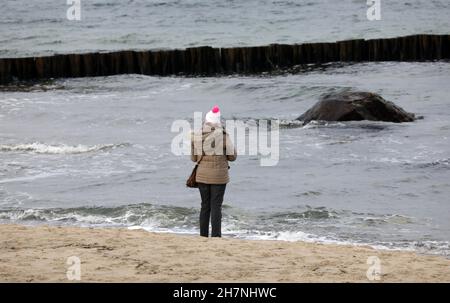 24 November 2021, Mecklenburg-Western Pomerania, Kühlungsborn: A walker stands on the almost deserted beach and looks at the Baltic Sea. Many clouds and drizzle provide classic North German dirty weather. Photo: Bernd Wüstneck/dpa-Zentralbild/ZB Stock Photo