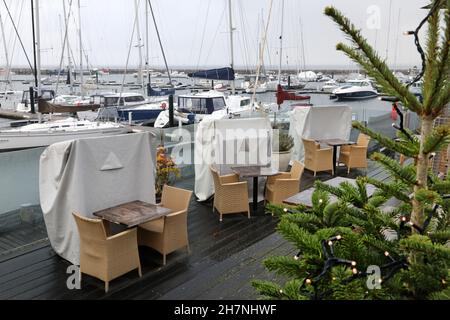 24 November 2021, Mecklenburg-Western Pomerania, Kühlungsborn: Weatherproof packed like at the last Corona Lockdown are the beach chairs in the outdoor area of a restaurant in the boat harbour. Many clouds and drizzle provide classic North German dirty weather. Photo: Bernd Wüstneck/dpa-Zentralbild/ZB Stock Photo