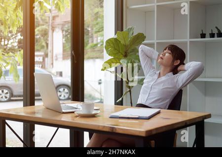 Young asian woman is stretching her shoulders during online meeting, webinar or online learning at home Stock Photo