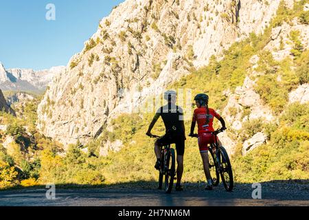Kemer, Turkey - November 11, 2021: man and woman cyclists look at a beautiful mountain valley
