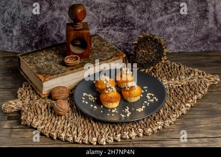 Small muffins topped with chopped almonds on a gray plate, with a wicker placemat and a wooden nutcracker Stock Photo