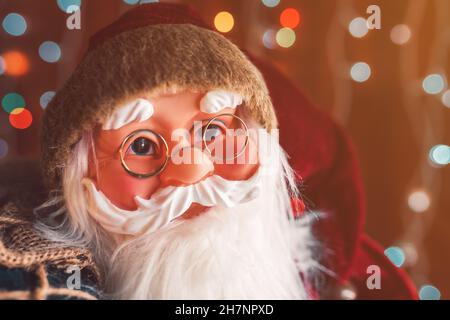 Santa Claus dummy toy with festive colorful string light bokeh background, selective focus Stock Photo