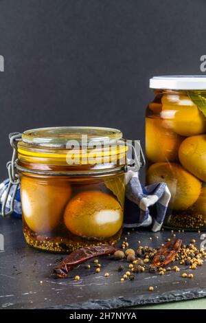 Two jars of eggs pickled in  dark malt vinegar, portrait with close up with pickling spices. Stock Photo