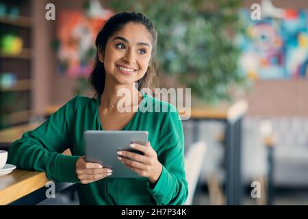 Attractive middle eastern woman having break at cafe, using pad Stock Photo