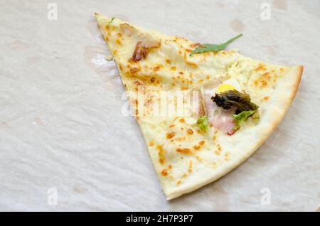 One slice of pizza in a large cardboard box. The last slice of pizza with herbs and bacon. Stock Photo