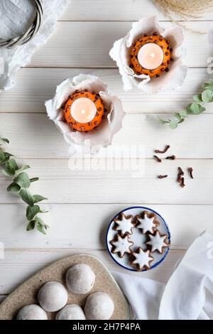 Eucalyptus twigs, candles in pomander ball oranges, scissors and gingerbread cookie on cutting board Stock Photo